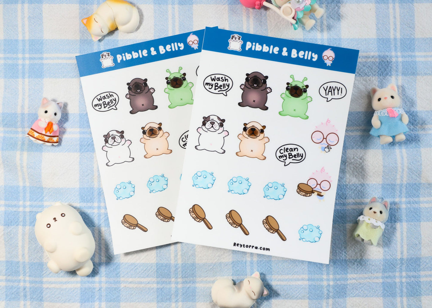 Two sheets of Pibble & Belly stickers on a blue checkered background with small plush toys. Features Pibble, Gmail, Washington, and Geeble. Frenchie puppy.